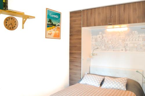 尼斯的住宿－Haliviera - Golden Square, 1min from beach，卧室配有一张床,墙上挂着一个钟