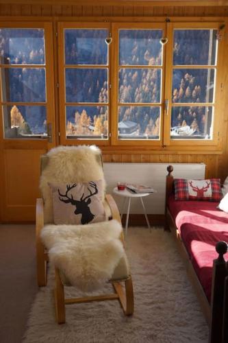 a room with a chair and a bed and windows at Vue à couper le souffle Arellaz 42 in Zinal