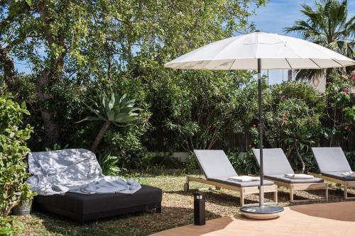 a patio with two chairs and an umbrella at The Carobs Villa in Carvoeiro