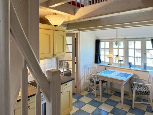 a kitchen with yellow cabinets and a table with chairs at Friesenhof, Haus Hafis, Whg 9 in Nebel