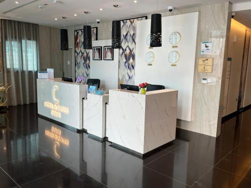 a reception desk in a lobby with clocks on the wall at C - Hotel and Suites Doha in Doha
