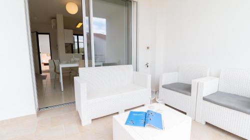 sala de estar con 2 sillas blancas y mesa en Welcomely - Civico 48, en Torre Grande