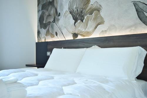 a bedroom with a white bed with a painting on the wall at Royal Garden luxury rooms in Padova