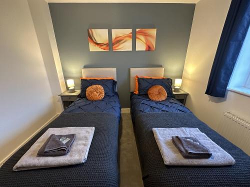 two beds sitting next to each other in a room at 3 Bed Home Sleeps 6 - Long Stays - Contractors & Relocators with Parking, Garden & WiFi in Milton Keynes