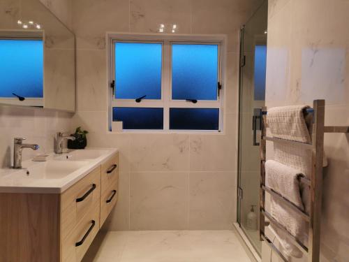 a bathroom with a sink and a shower with windows at House Located at the centre of East Auckland walking to Botany Westfield Shopping Mall in Auckland