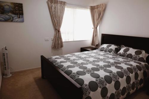 a bedroom with a bed and a window with curtains at House Located at the centre of East Auckland walking to Botany Westfield Shopping Mall in Auckland