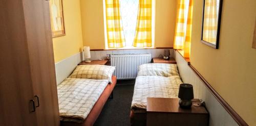 três camas num pequeno quarto com uma janela em penzion U Soudu em Liberec