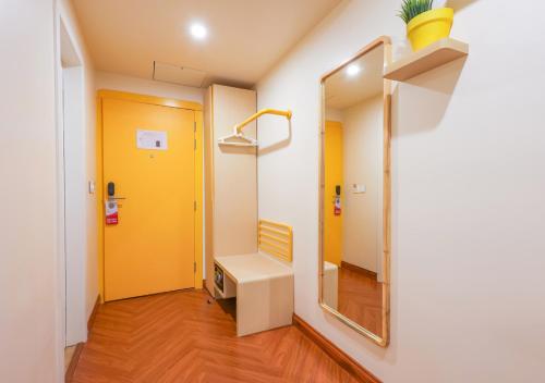 a hallway with a yellow door and a mirror at Bloom Hotel - Golf Course Road, Sector 43 in Gurgaon