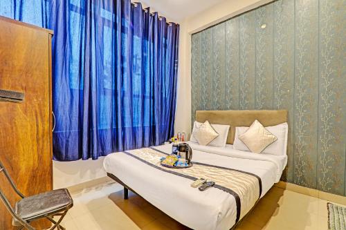 a bedroom with a bed and a chair and blue curtains at Hotel Agoura Prime in Lucknow