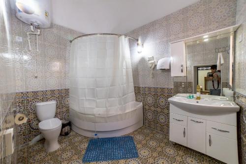 uma casa de banho com um chuveiro, um WC e um lavatório. em Feruzkhan Hotel - Madrassah Mohammed Rakhim Khan 1871 em Khiva