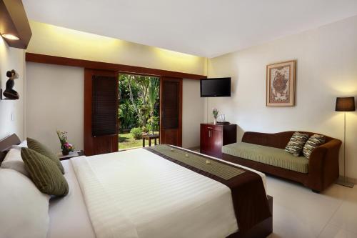 a bedroom with a large bed and a couch at Respati Beach Hotel in Sanur