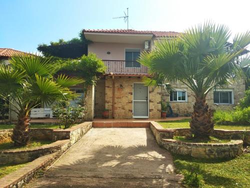 a house with two palm trees in front of it at Naturstein-Mediterranhaus mit Gartenblick in Flogita