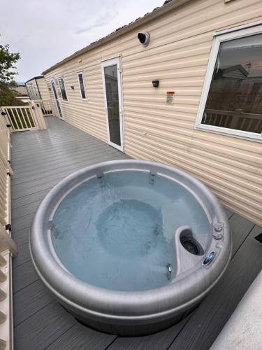 a hot tub sitting on a deck next to a house at My Leisure Home On Fantasy Island in Ingoldmells