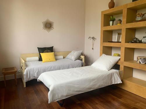 - une chambre avec 2 lits et une étagère dans l'établissement Suite privative Abella - Aile de maison bourgeoise, à Ambarès-et-Lagrave