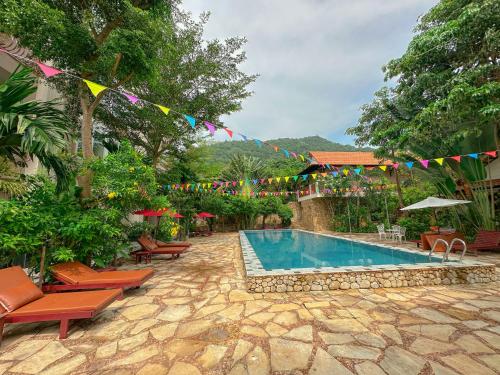 una piscina con banderas y sillas junto a un complejo en Summer Resort, en Kep