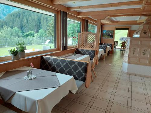 ein Restaurant mit Tischen und Stühlen und großen Fenstern in der Unterkunft Alpenpension Maderer in Gaschurn