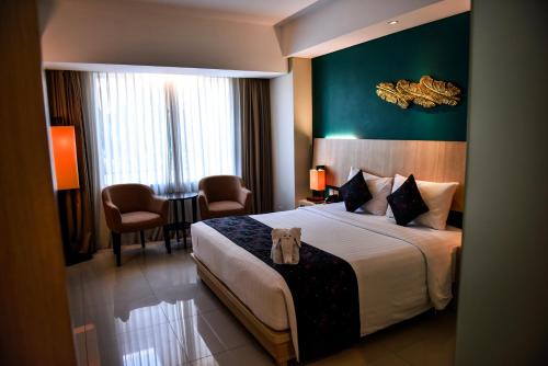 um quarto de hotel com uma cama, uma mesa e cadeiras em The Kana Kuta Hotel em Kuta