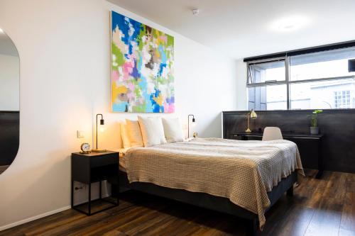 a bedroom with a bed and a painting on the wall at Modern Downtown 1 BR Apartment in Reykjavík