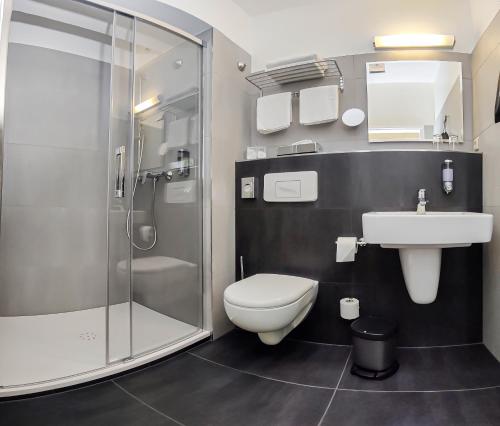 a bathroom with a shower and a toilet and a sink at Grünau Hotel in Berlin