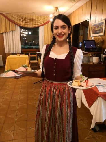 a woman is holding a plate of food at Hotel Bonapace ***S in Madonna di Campiglio