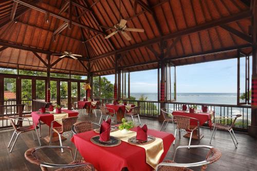a restaurant with red tables and chairs and the ocean at Respati Beach Hotel in Sanur