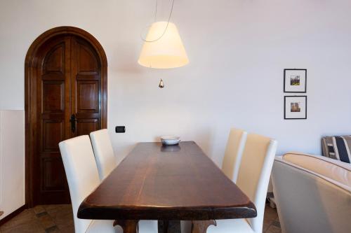 a dining room with a wooden table and white chairs at Apartment Merida in Belgirate