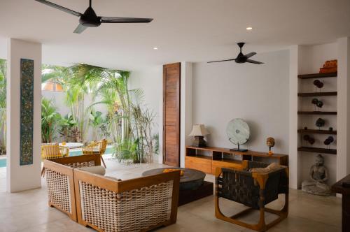 un soggiorno con ventilatore a soffitto e sedie di The Bed by The Sea a Canggu