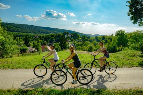 three women riding bikes down a dirt road at Prónay-kastély in Alsópetény