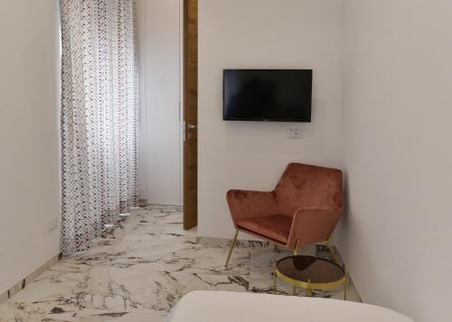 a room with a chair and a television on a wall at Hotel Exclusive in Agrigento