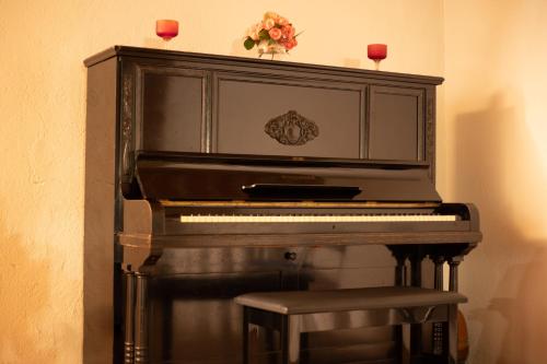 a black piano with a stool and two candles on top at Antica Casa Balsari in Borgo Ticino