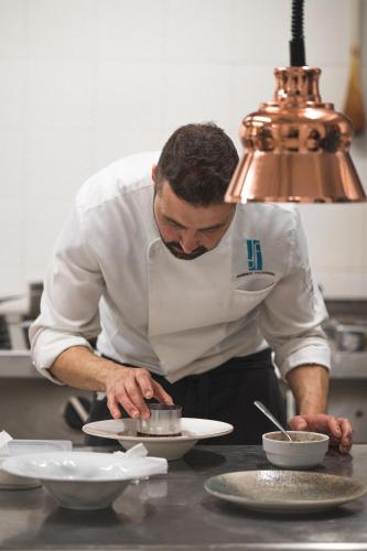a man in a kitchen preparing food on a plate at i Cacciagalli Wine Resort in Teano