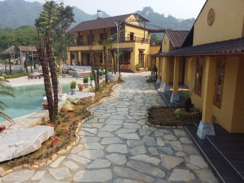 a stone walkway next to a building with a pool at Sky Bay Lodge in Ha Giang