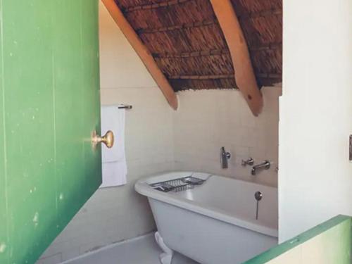 a bath tub in a bathroom with a green door at De Kleijne Bos in Paarl