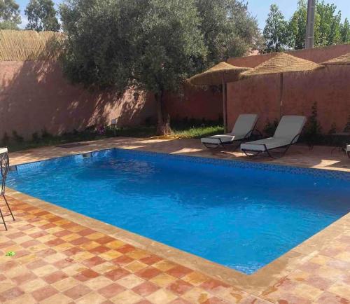 a blue swimming pool with two chairs and an umbrella at Villa privative tortues2 piscine chauffée 35min Marrakech in Marrakech
