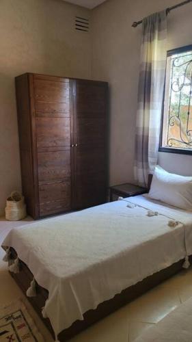 a bedroom with a bed and a wooden cabinet at Villa privative tortues2 piscine chauffée 35min Marrakech in Marrakech