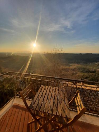a wooden bench on a balcony with the sun in the sky at Panoramico nell'antico borgo medievale di Casperia in Casperia