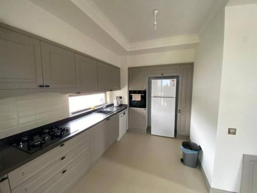eine Küche mit weißen Schränken und einem weißen Kühlschrank in der Unterkunft Moderne Villa in Kuşadası in Kusadası