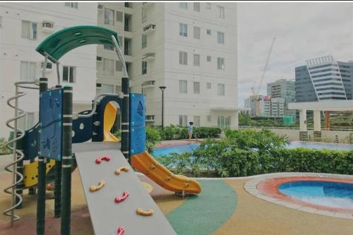 een speeltuin met een glijbaan in een zwembad bij Homey 2 BR Unit w/Pool in Avida IT Park in Cebu City