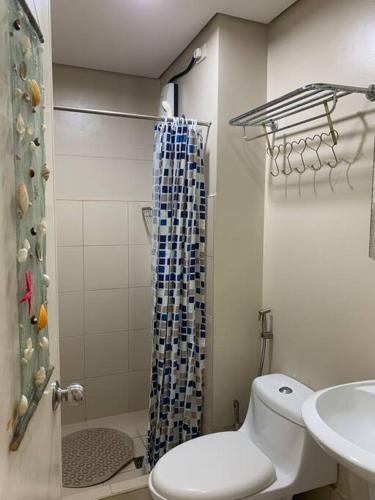 a bathroom with a toilet and a shower and a sink at Homey 2 BR Unit w/Pool in Avida IT Park in Cebu City
