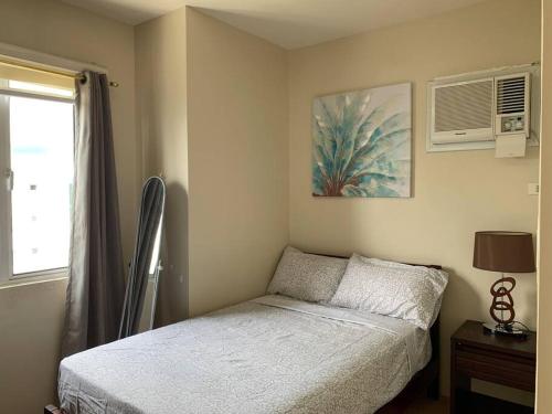 a small bedroom with a bed and a window at Homey 2 BR Unit w/Pool in Avida IT Park in Cebu City