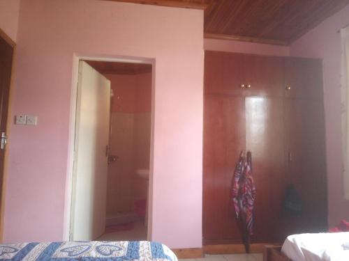 a bedroom with a pink wall and a bed at Key's Place in Ambira