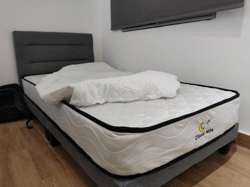un letto non fatto con lenzuola e cuscini bianchi di Stay Next to Stadium Axiata Arena Bukit Jalil a Kuala Lumpur