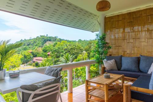 a balcony with a blue couch and a table and chairs at Kalani Bungalows, Haad Yao in Haad Yao