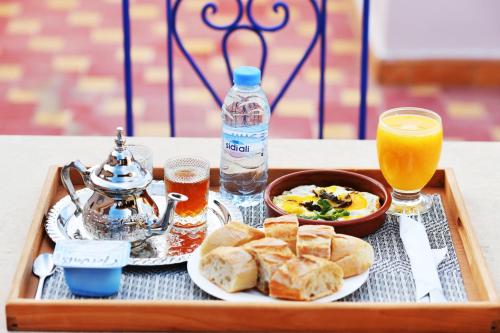 マラケシュにあるSOOFSTAY Guest-houseのパンとオレンジジュースと飲み物が入った食べ物のトレイ