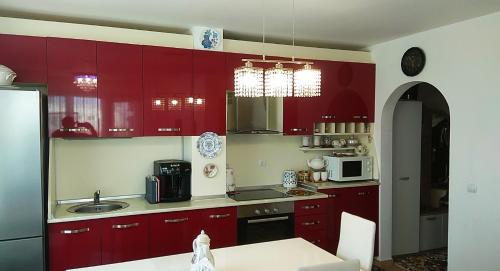 cocina con armarios rojos, fregadero y microondas en Прекрасный апартамент с видом на море и бассейном, en Byala