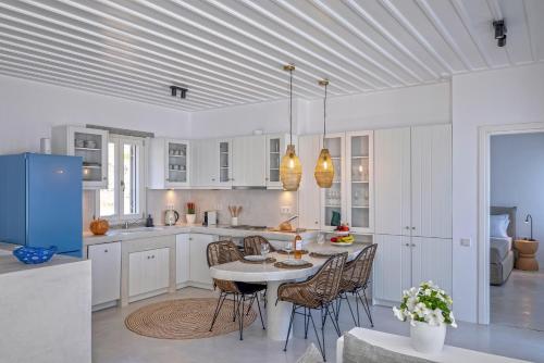a white kitchen with a table and chairs in it at Syros Grace eco-Villa with Jacuzzi & Stuning Views in Ano Syros