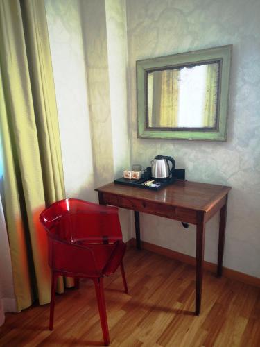 a red chair sitting next to a wooden desk with a mirror at ALBERGO BALDAZZI 1916 in Zavattarello