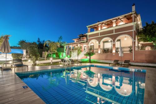a villa with a swimming pool in front of a house at Amalthia Villa in Mouzákion