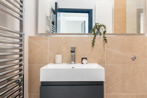 a bathroom with a white sink and a mirror at The Notting Hill Apartment in London