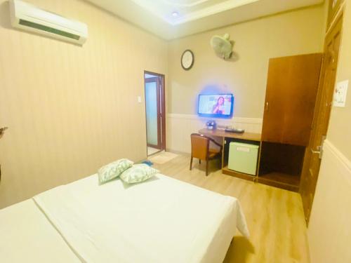 Schlafzimmer mit einem Bett, einem Schreibtisch und einem TV in der Unterkunft Nhu Y Hotel in Ho-Chi-Minh-Stadt